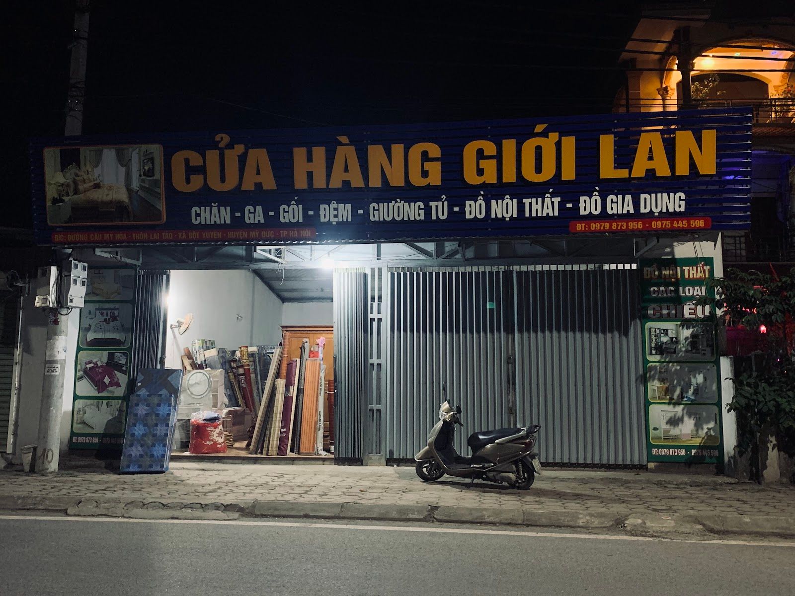 Mặt tiền cơ sở 2 về đêm, biển hiệu CỬA HÀNG GIỚI LAN: chăn ga gối đệm, giường tủ, đồ nội thất, đồ gia dụng.