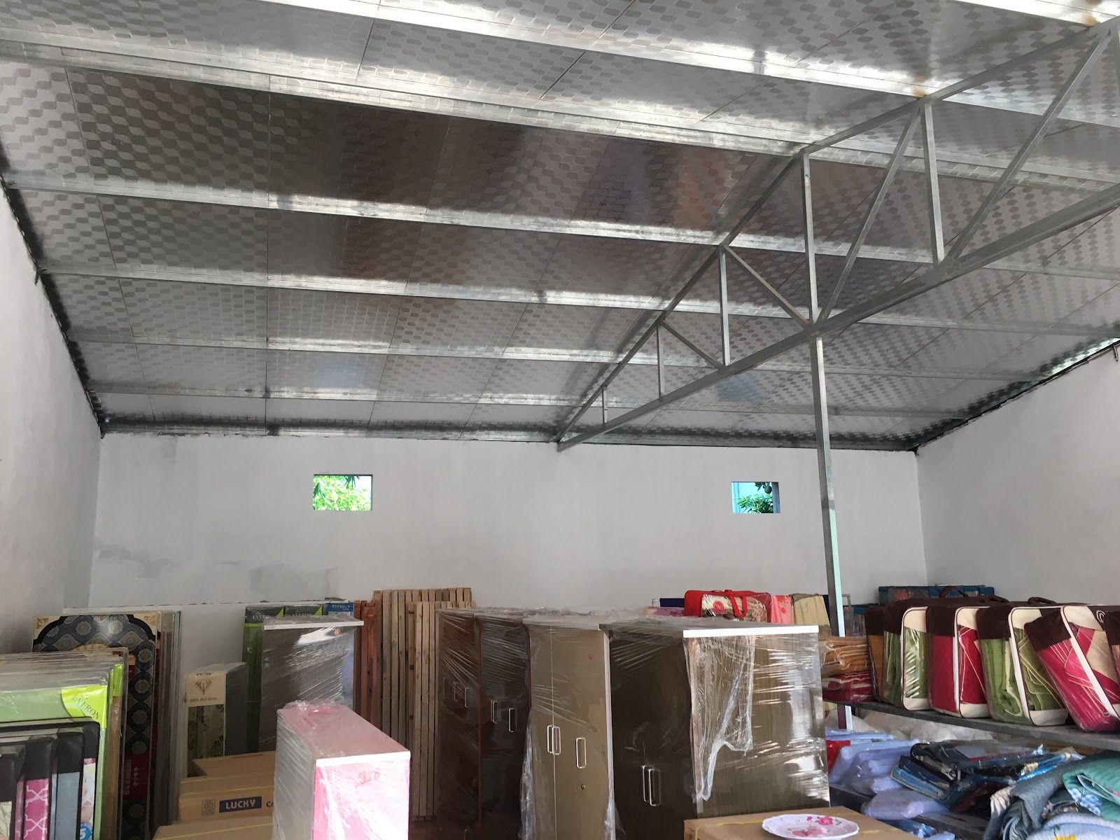 Gian hàng rộng, trần tôn, tủ và đồ nội thất đóng hộp phía cuối.